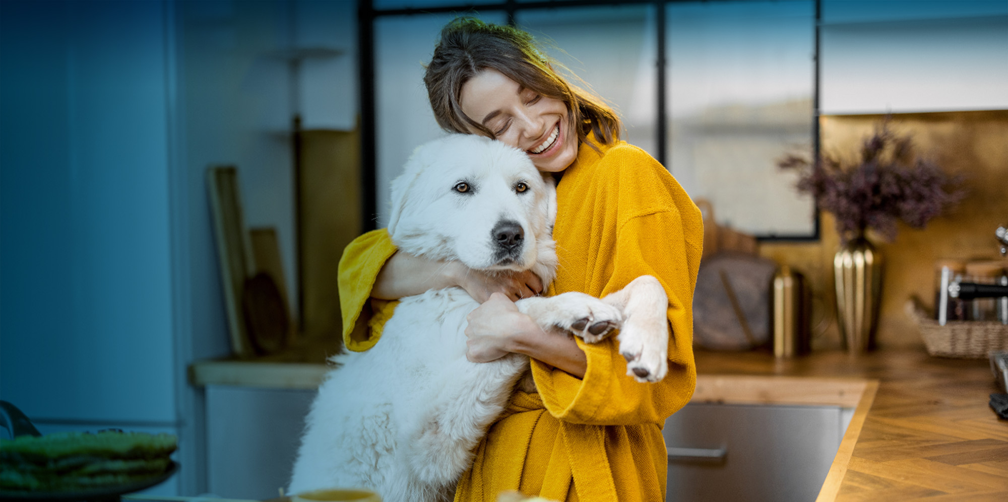 Woman smiling and holding dog in kitchen